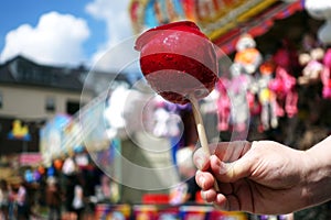 Sweet candy apple on county fair or festival. red candy apple covered in red caramel, at holiday vacation event or amusement park