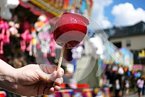 Sweet candy apple on county fair or festival. red candy apple covered in red caramel, at holiday vacation event or amusement park