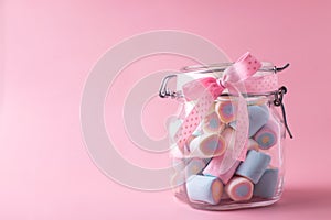 Sweet candy marshmallows  in  bank on jar on pink pastel background.