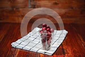 Sweet cherry, black cherries in a glass on wooden background