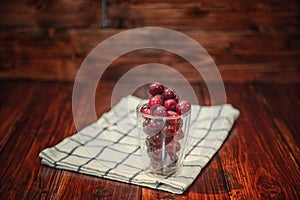 Sweet cherry black cherries in a glass on wooden background