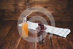 Sweet cherry, black cherries in a glass on wooden background with fresh juicy in glass bottle