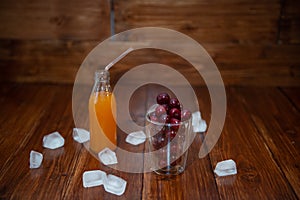 Sweet cherry, black cherries in a glass on wooden background with fresh juicy in glass bottle