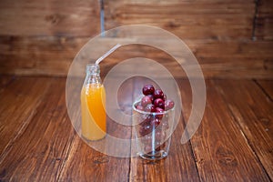 Sweet cherry, black cherries in a glass on wooden background with fresh juicy in glass bottle