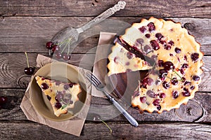 Sweet cherry clafouti on old wooden rustic background.