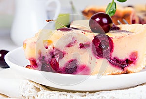 Sweet cherry clafouti. Piece of cake on wihite saucer