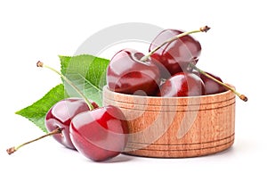 Sweet cherry with green leaves in a wooden plate on a white background. Isolated
