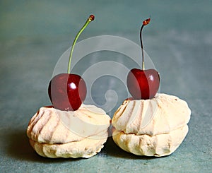 Sweet cherry and zefir on the blue table background