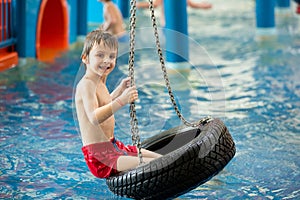 Sweet child, boy, playing in water world playground, enjoying at