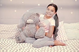 Sweet childhood. Girl child sit on bed with teddy bear in her bedroom. Kid prepare to go to bed. Pleasant time in cozy