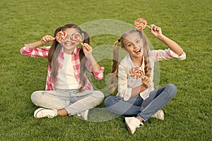 Sweet childhood. Happy children hold candy sit green grass. Candy shop. Lollipop treats. Candy synonym for happiness