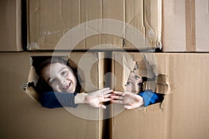 Sweet children,  boy brothers, hiding in cardboard box, looking out