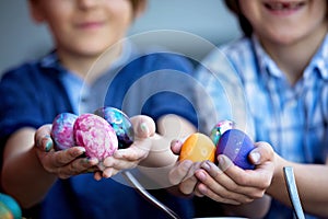 Sweet children, brothers, coloring and paiting eggs for Easter in garden, outdoor at home in backyard