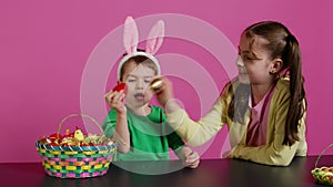 Sweet children knocking eggs together for easter tradition in studio,