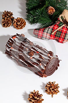 Sweet chocolate cake roll with pine branch, fir cones and Christmas stocking