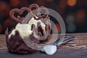 Sweet chocolate dessert with vanilla cream and chocolate hearts on wooden background with lights, product photography for patisser