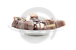 Sweet chocolate pralines. Tasty chocolate truffles on plate isolated on white background