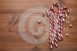 Sweet Christmas candy canes and festive decor on wooden table, flat lay. Space for text