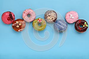 Sweet colored donuts on a blue background, laid out in the form of various geomitric figure, arrow, square, line photo