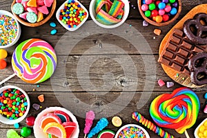 Sweet and colorful candy buffet frame, overhead view table scene with a rustic wood background