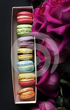 Sweet colorful macaroons and roses on black