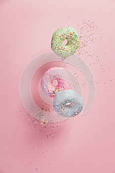 Sweet and colourful doughnuts with sprinkles falling or flying i