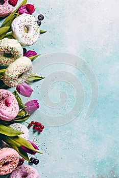 Sweet and colourful doughnuts with sprinkles, purple tulips and