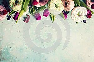 Sweet and colourful doughnuts with sprinkles, purple tulips and