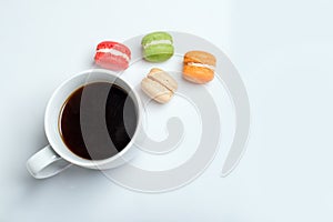 Sweet and colourful macaroons with cup of coffee on white background. Traditional french dessert. Top view, flat lay