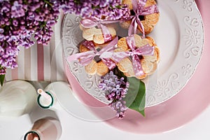 Sweet cookies with pink ribbon, lilac flowers and chocolate milk