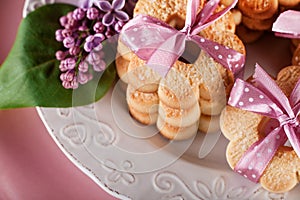 Sweet cookies with pink ribbon and lilac flowers, top view