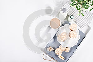 Sweet cookies on white tray with bottles of milk and flowers fro