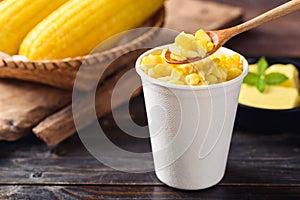 Sweet corn with butter in a biodegradable cup eating by spoon