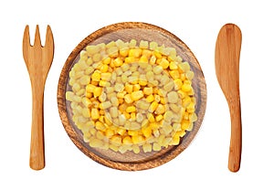 Sweet corn grain on wooden plate, fork and knife isolated