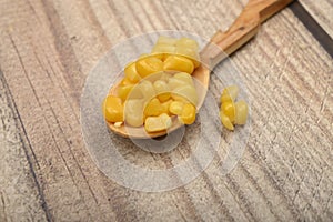Sweet corn kernels on a wooden spoon on a wooden table. Fitness diet. Healthy diet. For a sweet treat. Close up