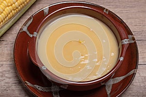 Sweet corn soup in a ceramic cup on wooden background