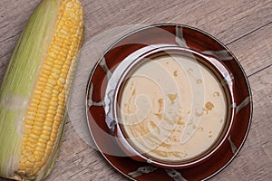 Sweet corn soup in a ceramic cup on wooden background