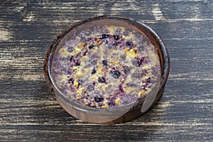 Sweet cottage cheese casserole with black currant and semolina on wooden table. Ceramic bowl with baked cottage cheese casserole