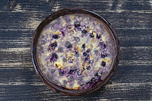 Sweet cottage cheese casserole with black currant and semolina on wooden table. Ceramic bowl with baked cottage cheese casserole