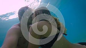 Sweet couple kissing under the water in the ocean (slow motion)