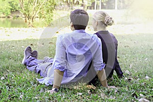 Sweet couple sitting on green grass in park  young beautiful lover spending time together and having romantic moment in summer