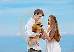Sweet couple of young lovers with a dog resting on the beach