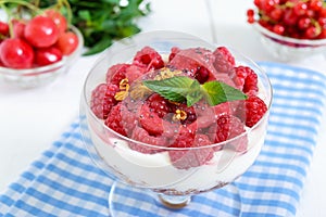 Sweet creamy dessert with granola, cream cheese, fresh raspberries in a glass bowl