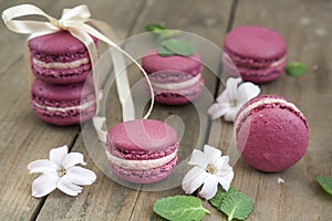 Sweet crimson french macaroons wiht hyacinth flowers and mint on dark wooden background