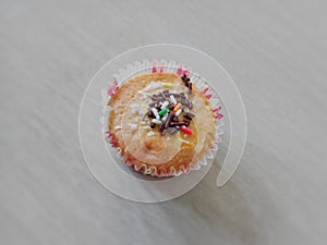 Sweet cupcake with sugar and meces ceres topping lying on the floor photo