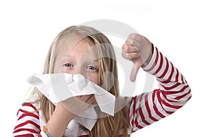 Sweet and cute blond hair little girl blowing her nose with paper tissue having a cold feeling sick