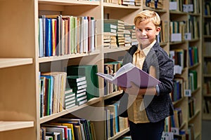 sweet cute school boy smiling while reading a book