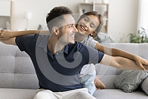 Sweet daughter child playing flying airplane with happy daddy