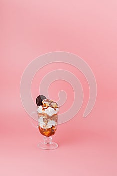 Sweet dessert in glass with biscuit and whipped cream on pink bsckground, selective focus and blank space