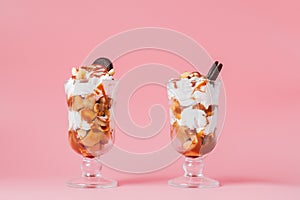 Sweet dessert in glass with biscuit and whipped cream on pink bsckground, selective focus and blank space